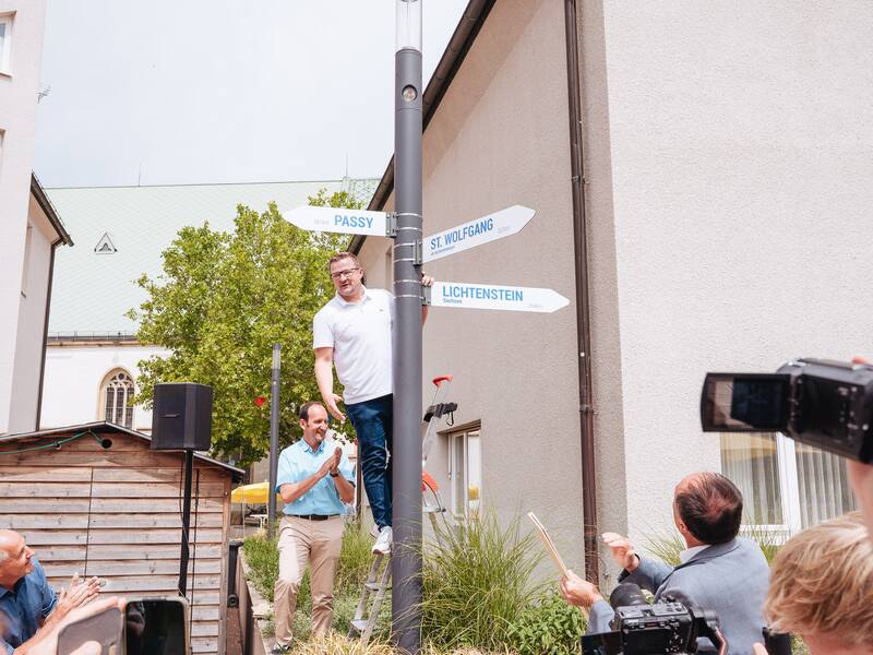 Passyjubiläum 29 - Stefan Wörner, unterstützt von Dekan Hermann Friedel unten, enthüllt den Wolfgang-Wegweiser