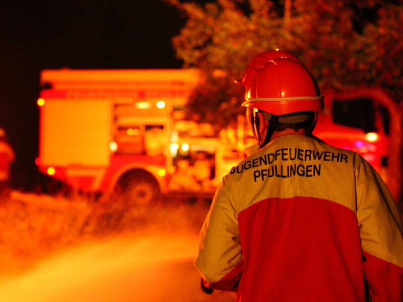 Jugendfeuerwehrangehöriger bei Dunkelheit vor einem Löschfahrzeug